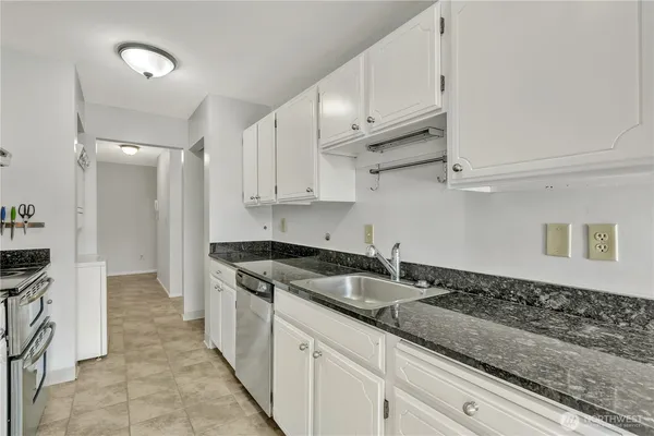 a kitchen with granite countertop a sink and white cabinets