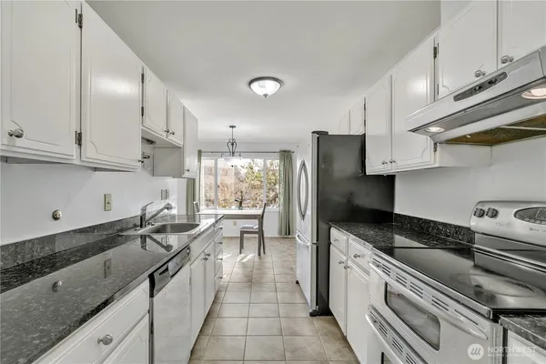 a kitchen with granite countertop a sink a counter space stainless steel appliances and cabinets
