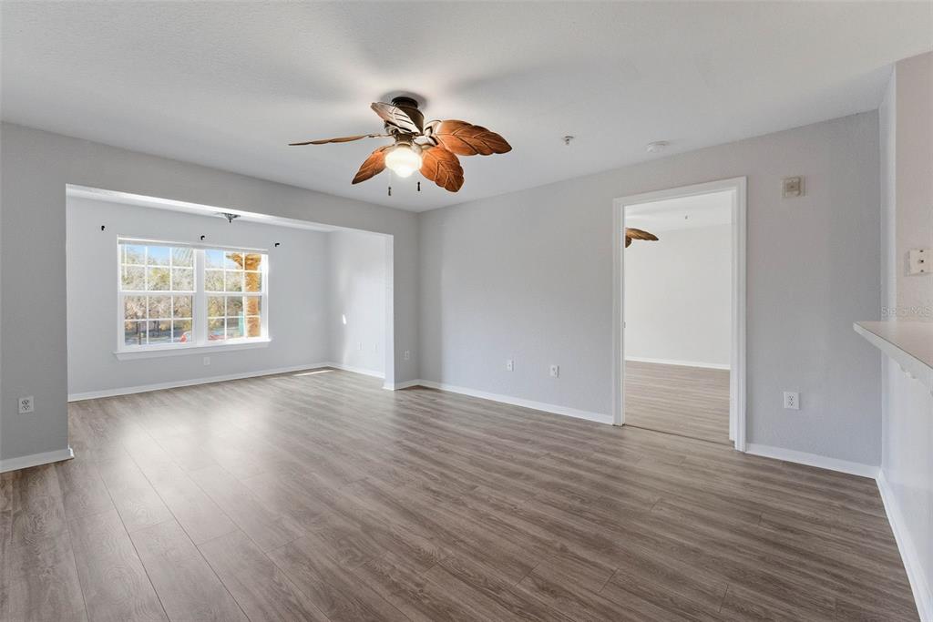 5479 Vineland Road, Unit 9202 Orlando, FL 32811 - Photo 12 of 31 an empty room with wooden floor chandelier fan and windows