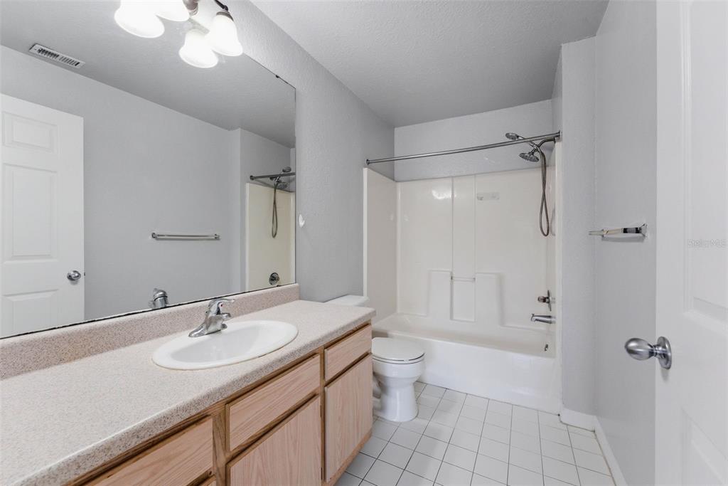 5479 Vineland Road, Unit 9202 Orlando, FL 32811 - Photo 26 of 31 a bathroom with a granite countertop sink a toilet and shower