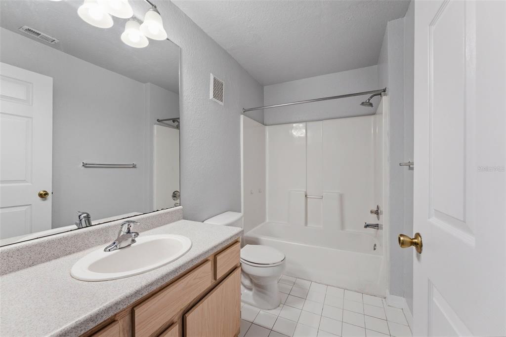5479 Vineland Road, Unit 9202 Orlando, FL 32811 - Photo 27 of 31 a bathroom with a granite countertop sink a toilet a mirror and a shower