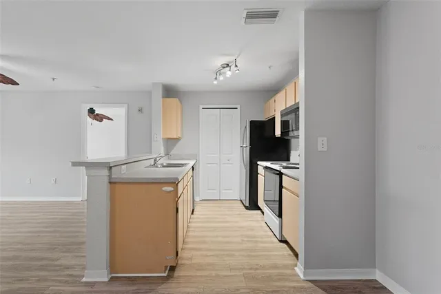 a kitchen with stainless steel appliances granite countertop a refrigerator a stove and a sink