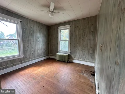 a view of an empty room with a window and wooden floor