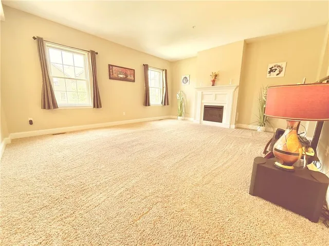 a view of an empty room with window and a kitchen