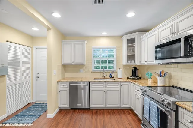 a kitchen with stainless steel appliances granite countertop wooden cabinets granite counter tops and a hard wood floors