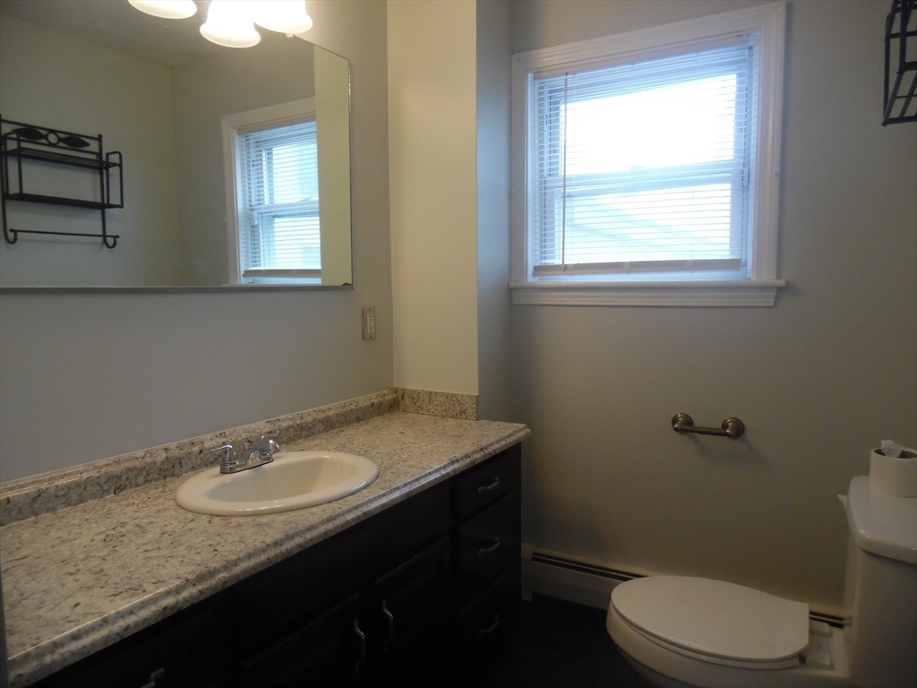 1226 North Main Street, Unit 1 Fall River, MA 02720 - Photo 8 of 10 a bathroom with a granite countertop sink toilet and a window