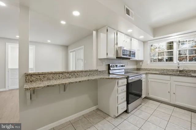 a kitchen with stainless steel appliances granite countertop a stove a sink and a microwave