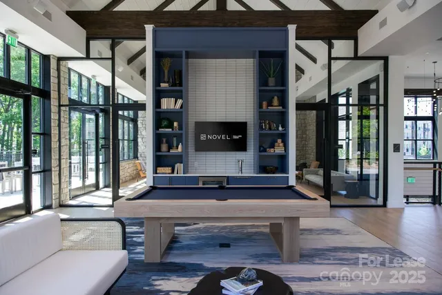 a living room with furniture a flat screen tv and floor to ceiling window