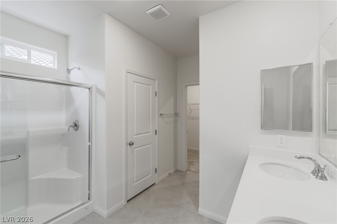 3765 Osiris Avenue Henderson, NV 89044 - Photo 28 of 40 Bathroom with double vanity, a stall shower, and a spacious closet