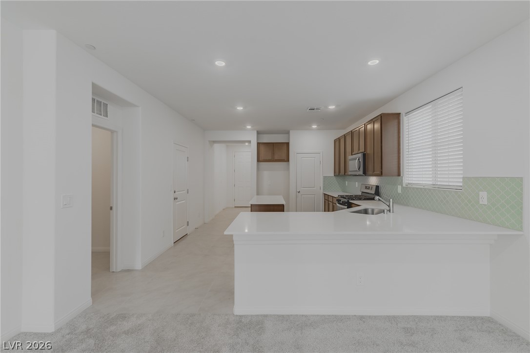 3765 Osiris Avenue Henderson, NV 89044 - Photo 33 of 40 Kitchen featuring a peninsula, stainless steel appliances, recessed lighting, light colored carpet, and wood finish cabinetry