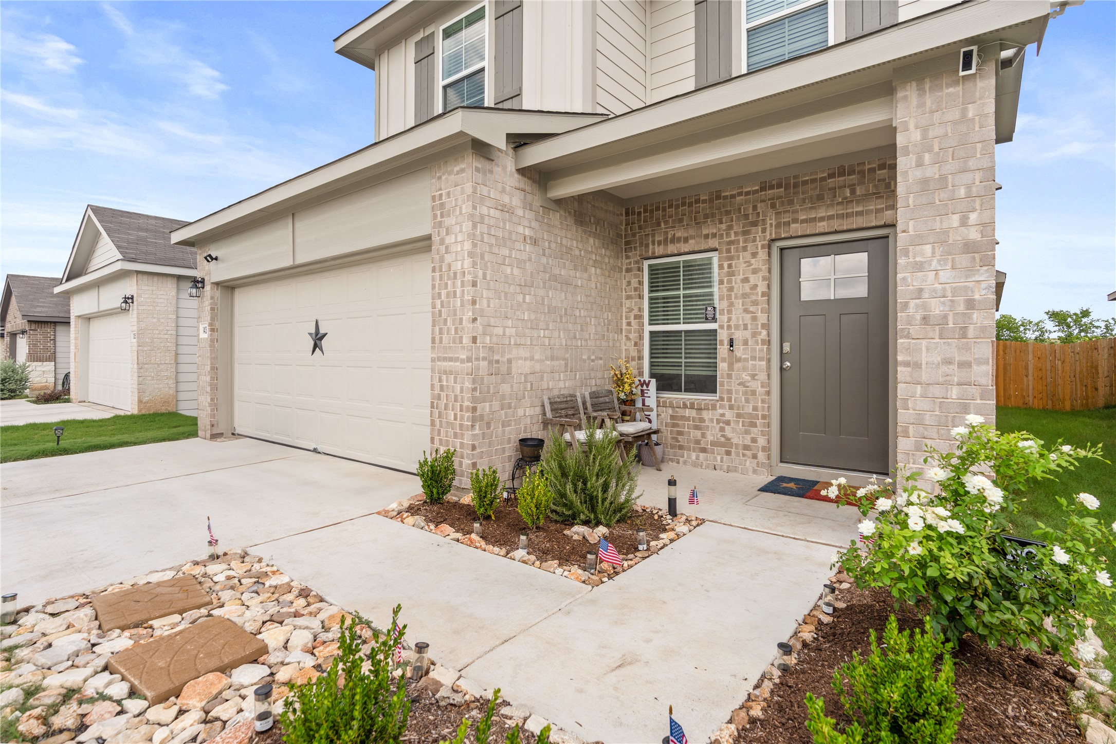 143 Santa Rosa Lane Buda, TX 78610 - Photo 3 of 28 Doorway to property with brick siding, a garage, concrete driveway, and board and batten siding