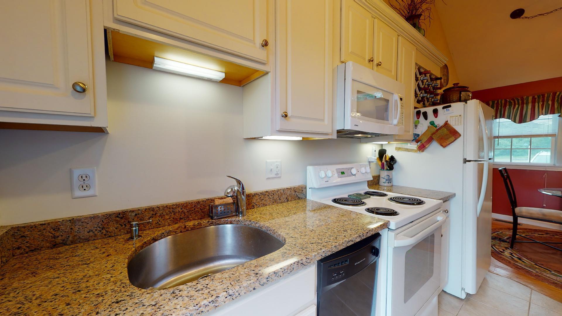 6 Shore Road, Unit 24 Truro, MA 02666 - Photo 25 of 46 a kitchen with granite countertop a sink a stove and cabinets