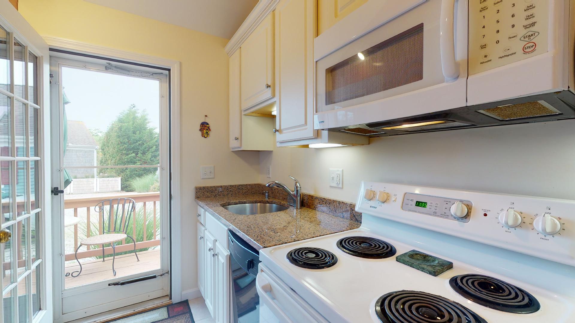 6 Shore Road, Unit 24 Truro, MA 02666 - Photo 27 of 46 a kitchen with a stove a microwave and wooden floor