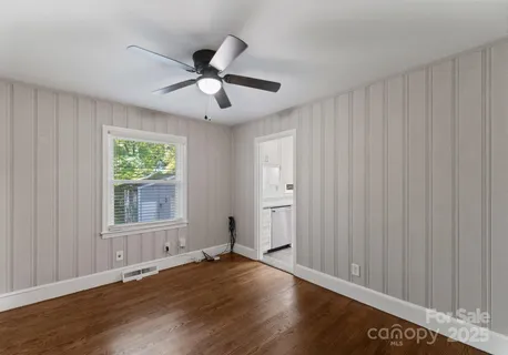 a view of an empty room with a window and wooden floor