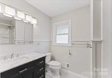 a bathroom with a granite countertop sink a toilet and a mirror