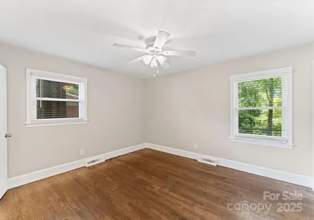 a view of empty room with wooden floor and fan