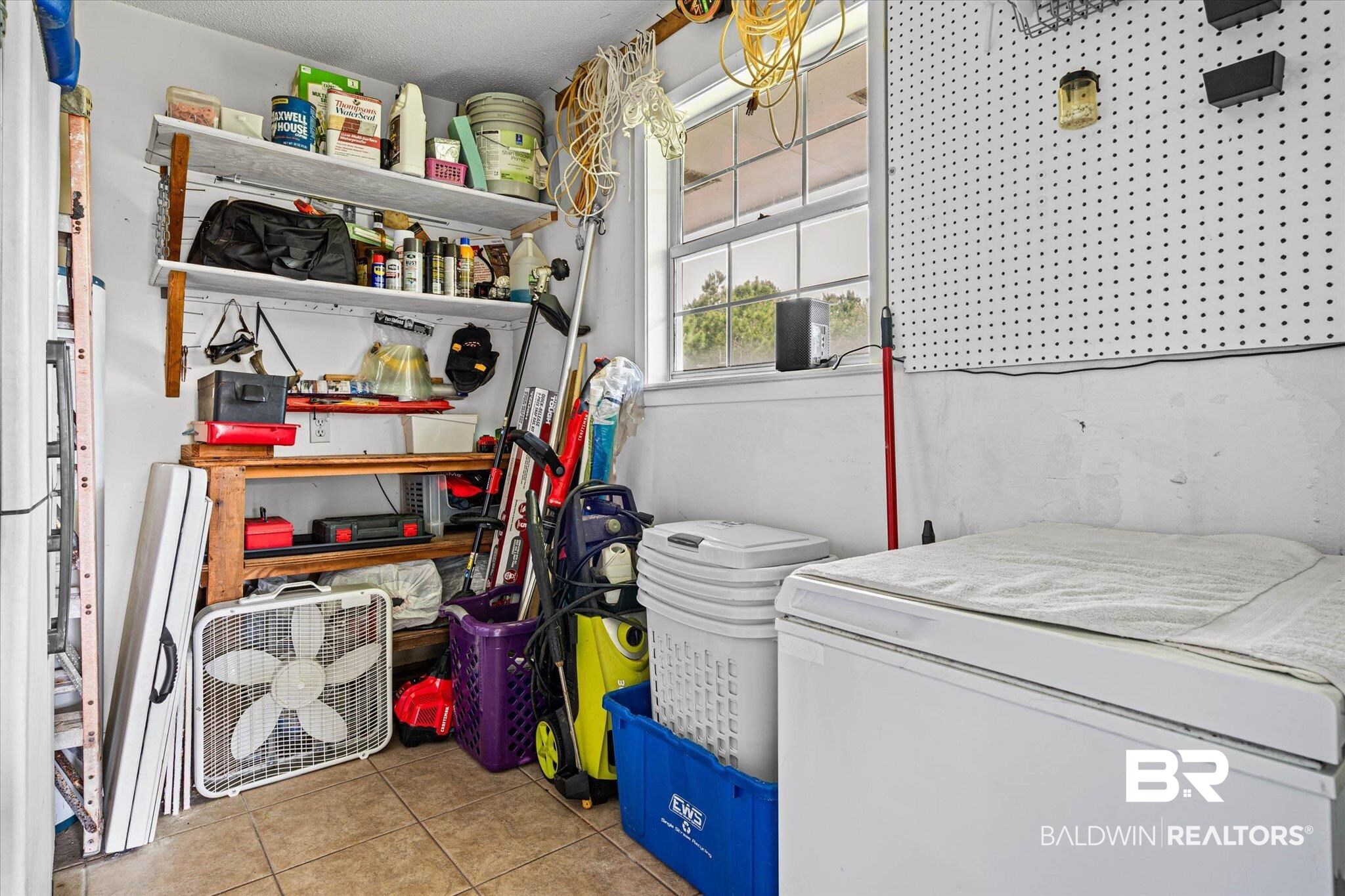9100 Shell Belt Road Coden, AL 36523 - Photo 20 of 38 Utility room featuring tile flooring, built-in shelving, pegboard wall storage, and a single window