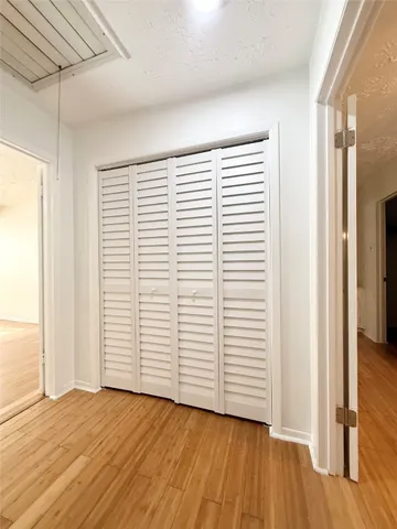 a view of empty room with wooden floor and fan