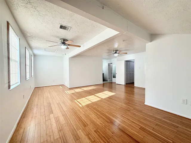 a view of a room with wooden floor and a ceiling fan