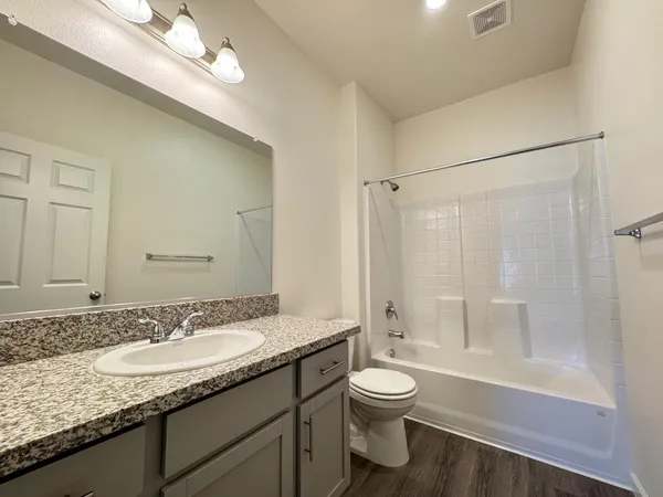 a bathroom with a granite countertop sink a toilet and shower