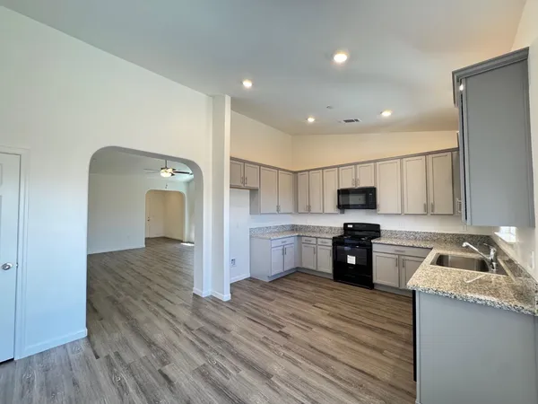 a kitchen with stainless steel appliances granite countertop a refrigerator a stove top oven a sink dishwasher and wooden floor