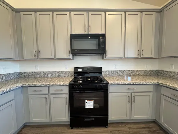 a kitchen with granite countertop white cabinets and a stove top oven