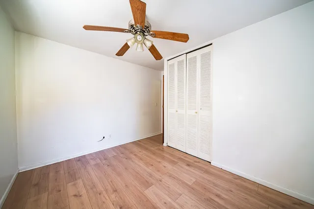 an empty room with wooden floor and fan