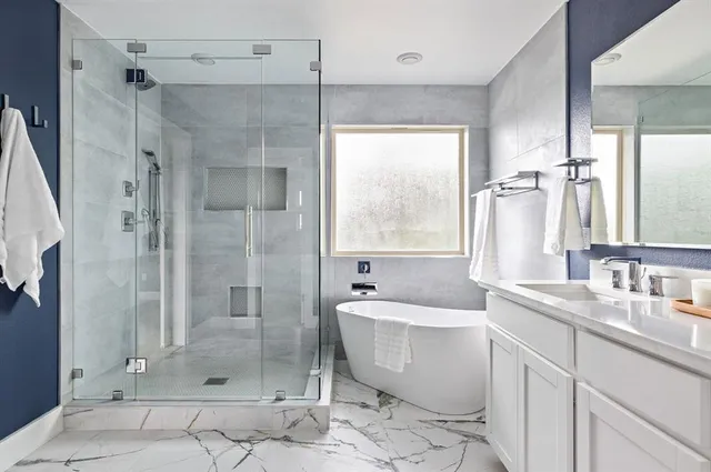 a bathroom with a granite countertop bathtub shower sink vanity and toilet