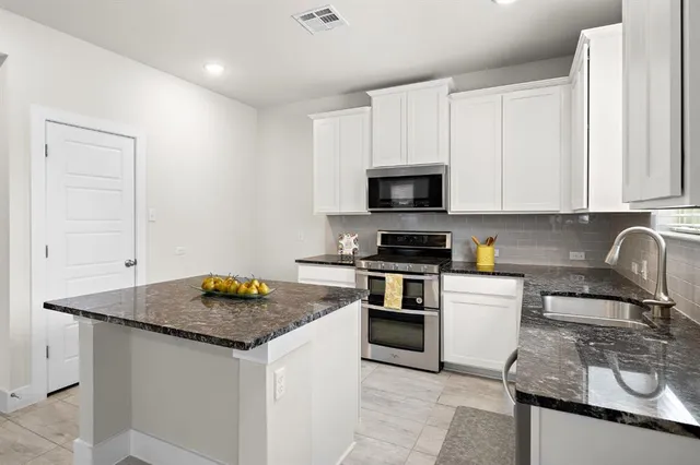 a kitchen with granite countertop a sink stove and cabinets