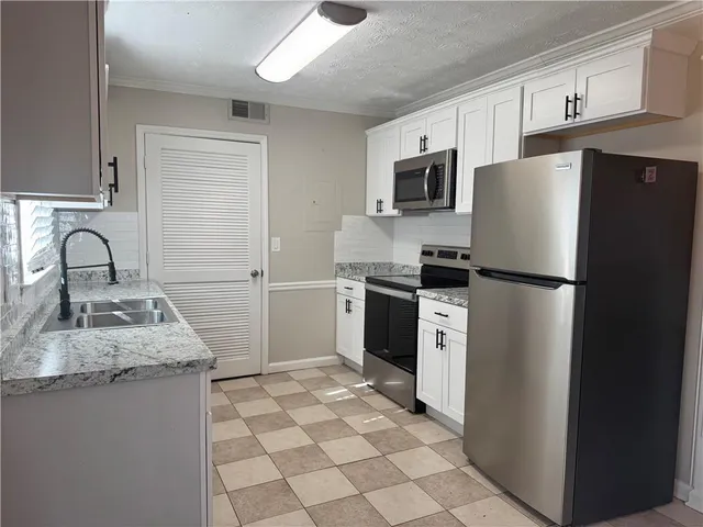 a kitchen with granite countertop a refrigerator sink stove and microwave