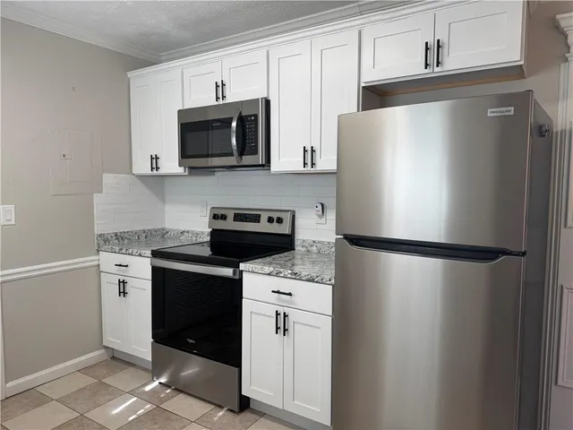 a white refrigerator freezer and a stove sitting inside of a kitchen with stainless steel appliances granite countertop cabinets and a refrigerator