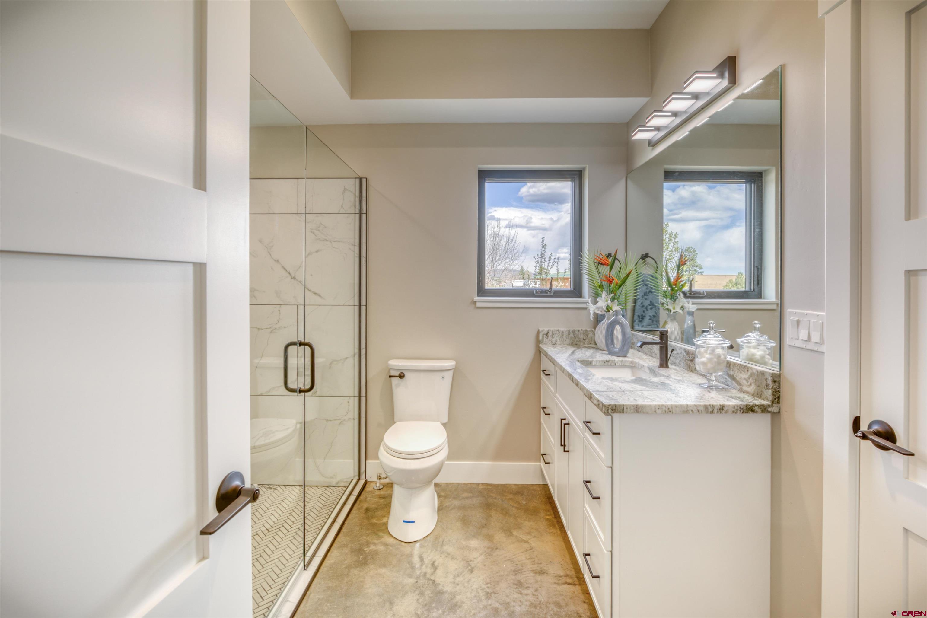 2790 Rock Road, Unit B Pagosa Springs, CO 81147 - Photo 15 of 43 a spacious bathroom with a granite countertop sink toilet a mirror and a shower