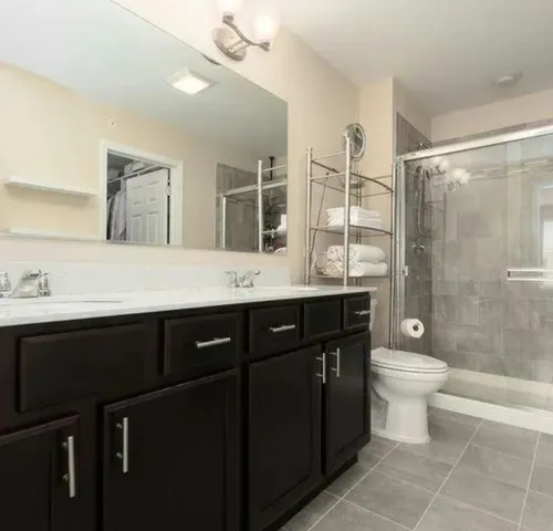 a bathroom with a sink a toilet a mirror and shower