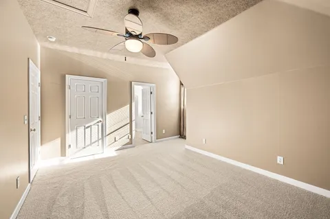 a view of an empty room with a ceiling fan and window