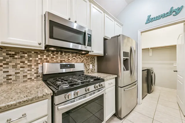 a kitchen with stainless steel appliances granite countertop a stove a refrigerator and a microwave