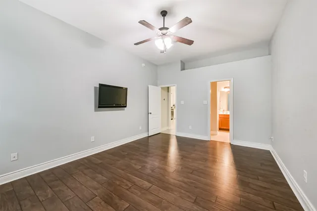 an empty room with wooden floor and ceiling fan