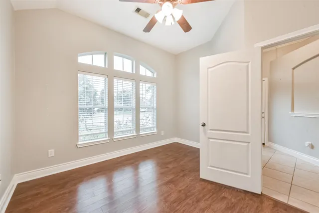 an empty room with wooden floor cabinet and windows