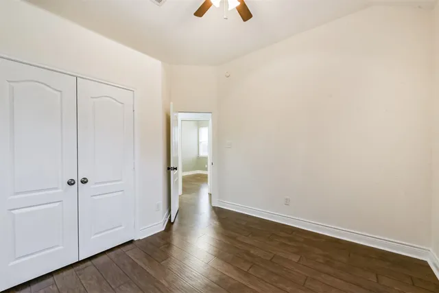 a view of an empty room and wooden floor chandelier fan
