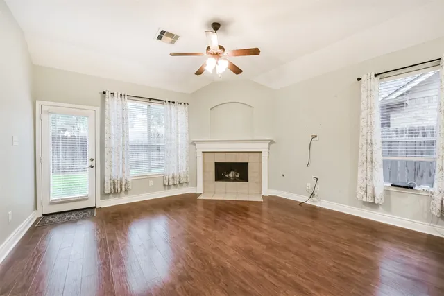 a view of an empty room with wooden floor fireplace and a window