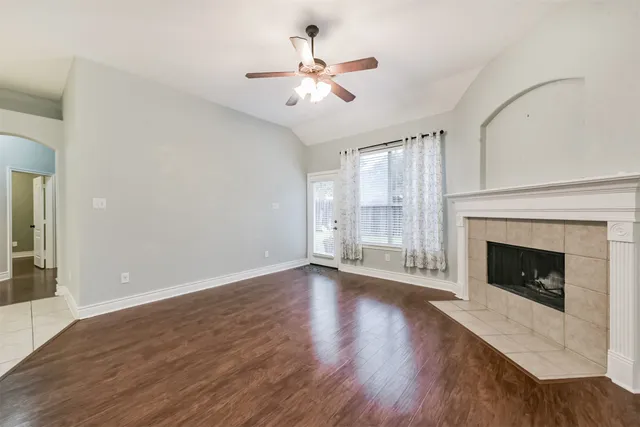 a view of an empty room with wooden floor fireplace and a window