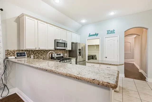 a kitchen with granite countertop a sink a stove and cabinets