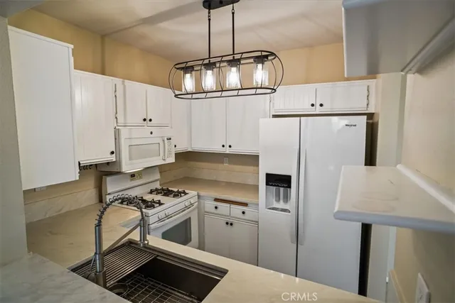 a kitchen with stainless steel appliances a refrigerator a stove a sink and white cabinets
