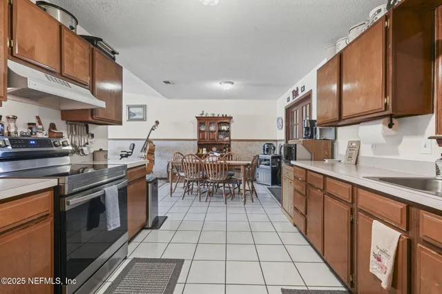 a kitchen with stainless steel appliances granite countertop a stove top oven a sink a dining table and chairs