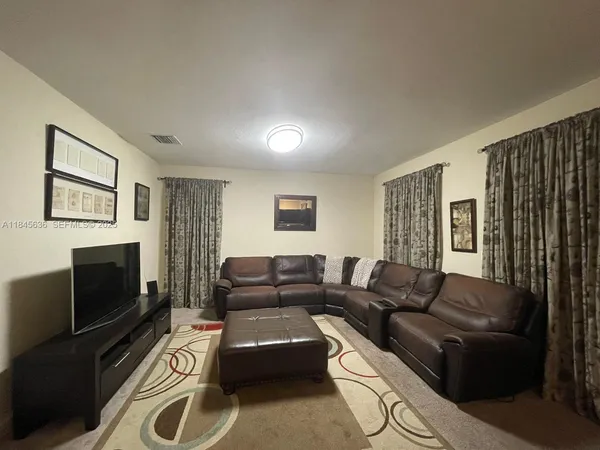 a living room with furniture a flat screen tv and a window