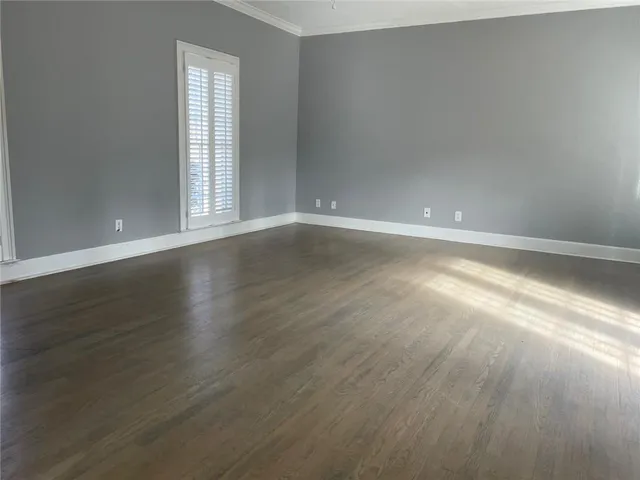 an empty room with wooden floor and windows with curtains