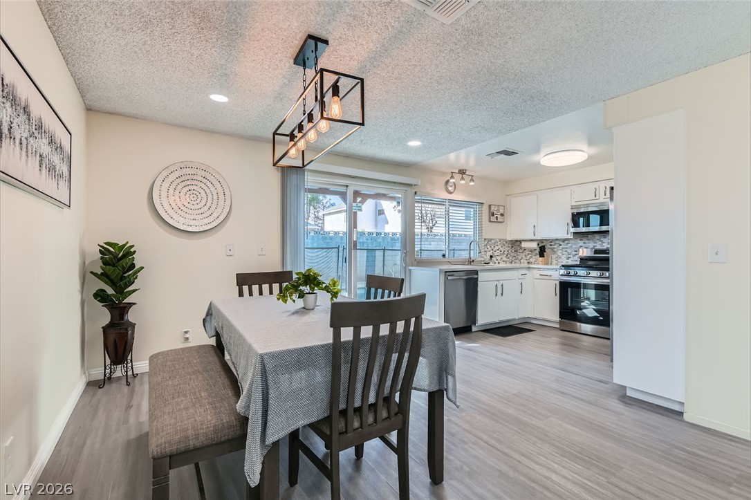 3665 Bronco Road Las Vegas, NV 89103 - Photo 8 of 28 An inviting eat-in kitchen with bright white cabinetry and sleek stainless steel appliances.