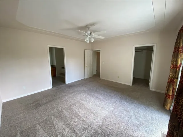 a view of a big room with windows and chandelier fan