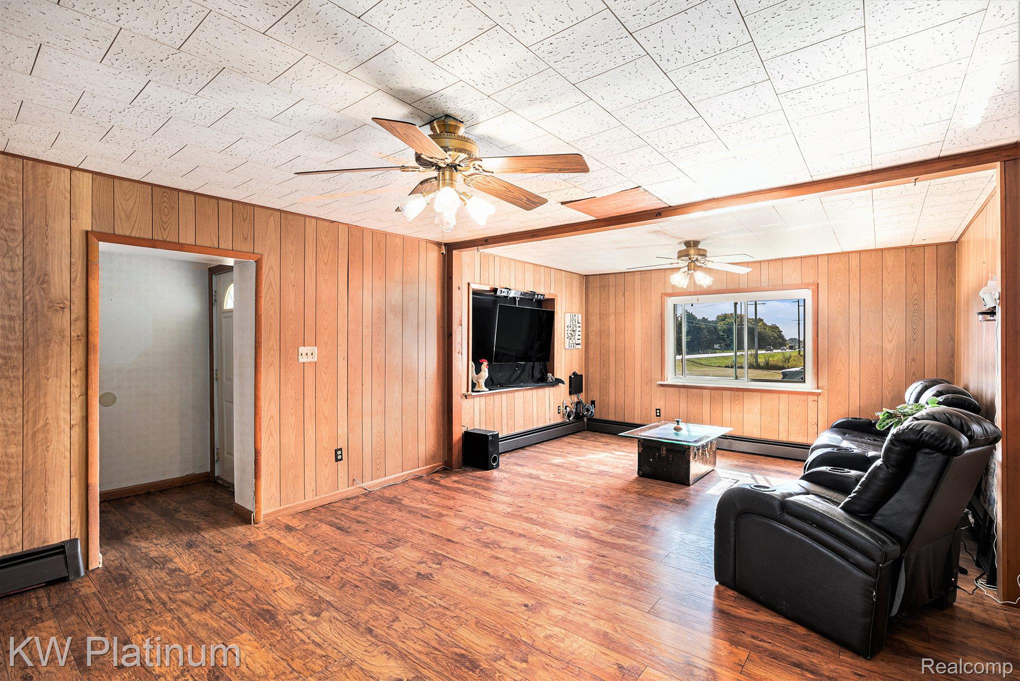 8060 Brockway Road Melvin, MI 48454 - Photo 5 of 39 Living area featuring wood walls, wood finished floors, ceiling fan, and a baseboard radiator