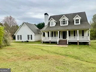 a view of a white house with a large pool lawn chairs and a yard with swimming pool