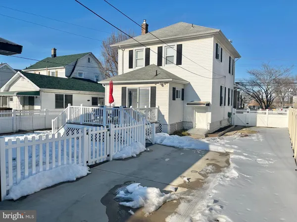 a view of a white house with a small yard and wooden fence